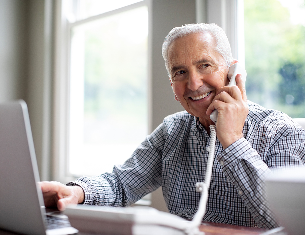 man on landline phone in front of computer