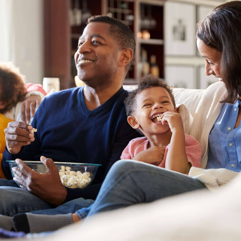 family on couch watching movie with popcorn