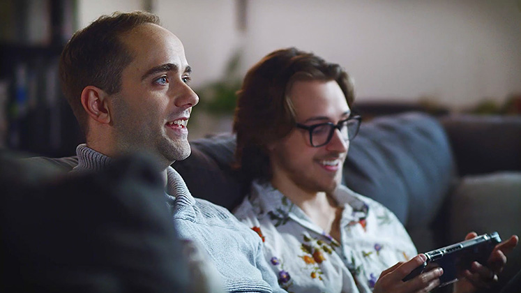 Two men relaxing on a couch playing video games, representing Blue Ridge’s fast and reliable internet for multiple connected devices.