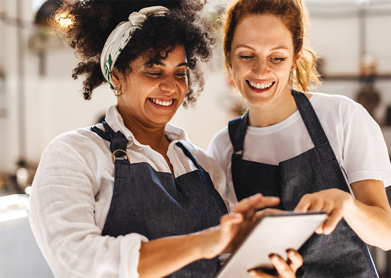 Two business employees smiling and looking at a tablet while setting up their eero for Business WiFi.
